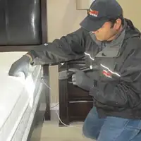 Bed bug inspection technician checking a mattress and bed frame for signs of infestation in Cedar Rapids, IA