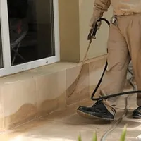 General pest control technician spraying exterior perimeter around a home in Cedar Rapids, IA