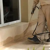 General pest control technician spraying exterior perimeter around a home in Cedar Rapids, IA