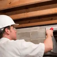 Termite inspection technician checking a basement wall and framing for termite activity in Cedar Rapids, IA